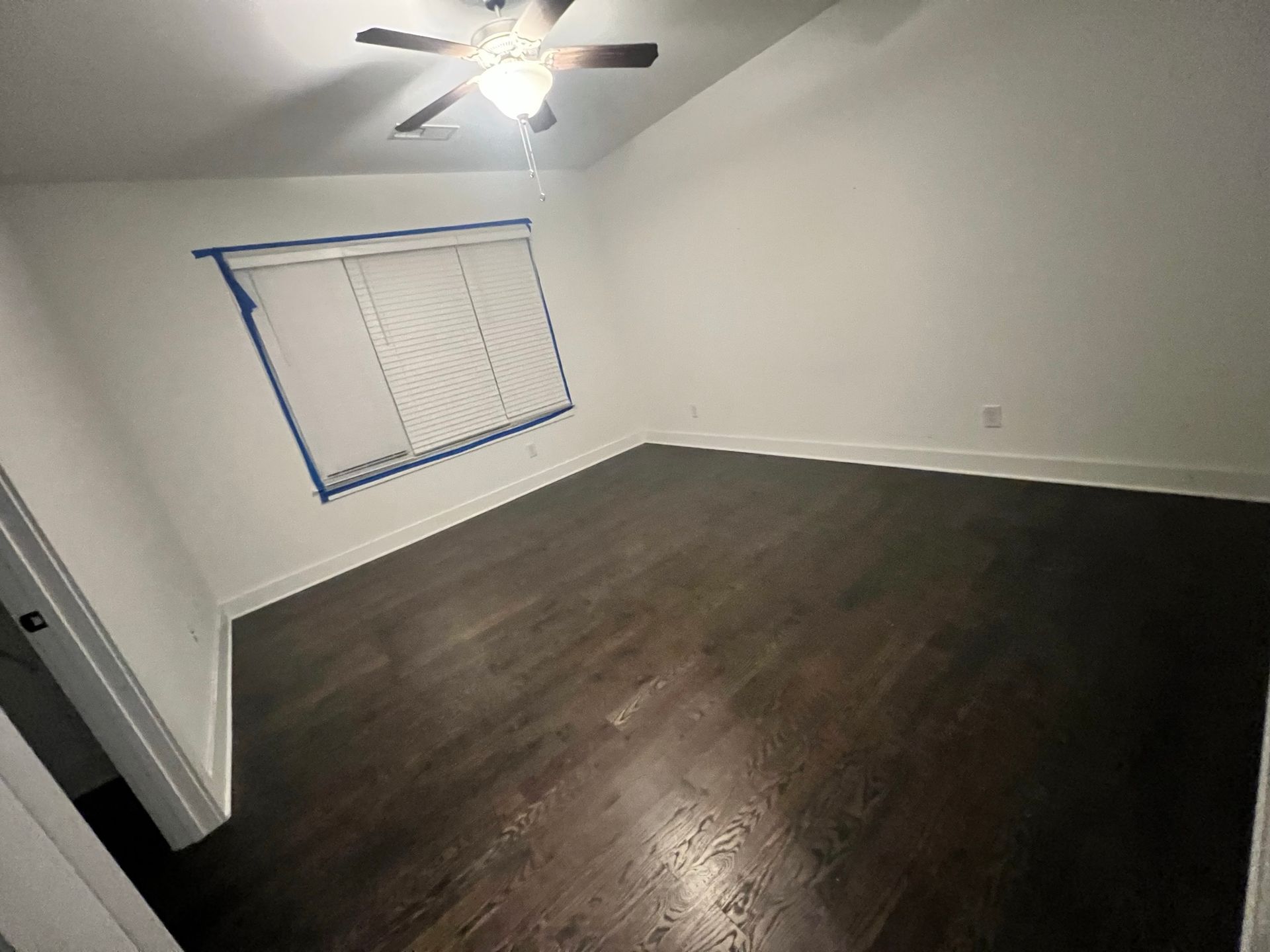 An empty bedroom with a ceiling fan and a window.