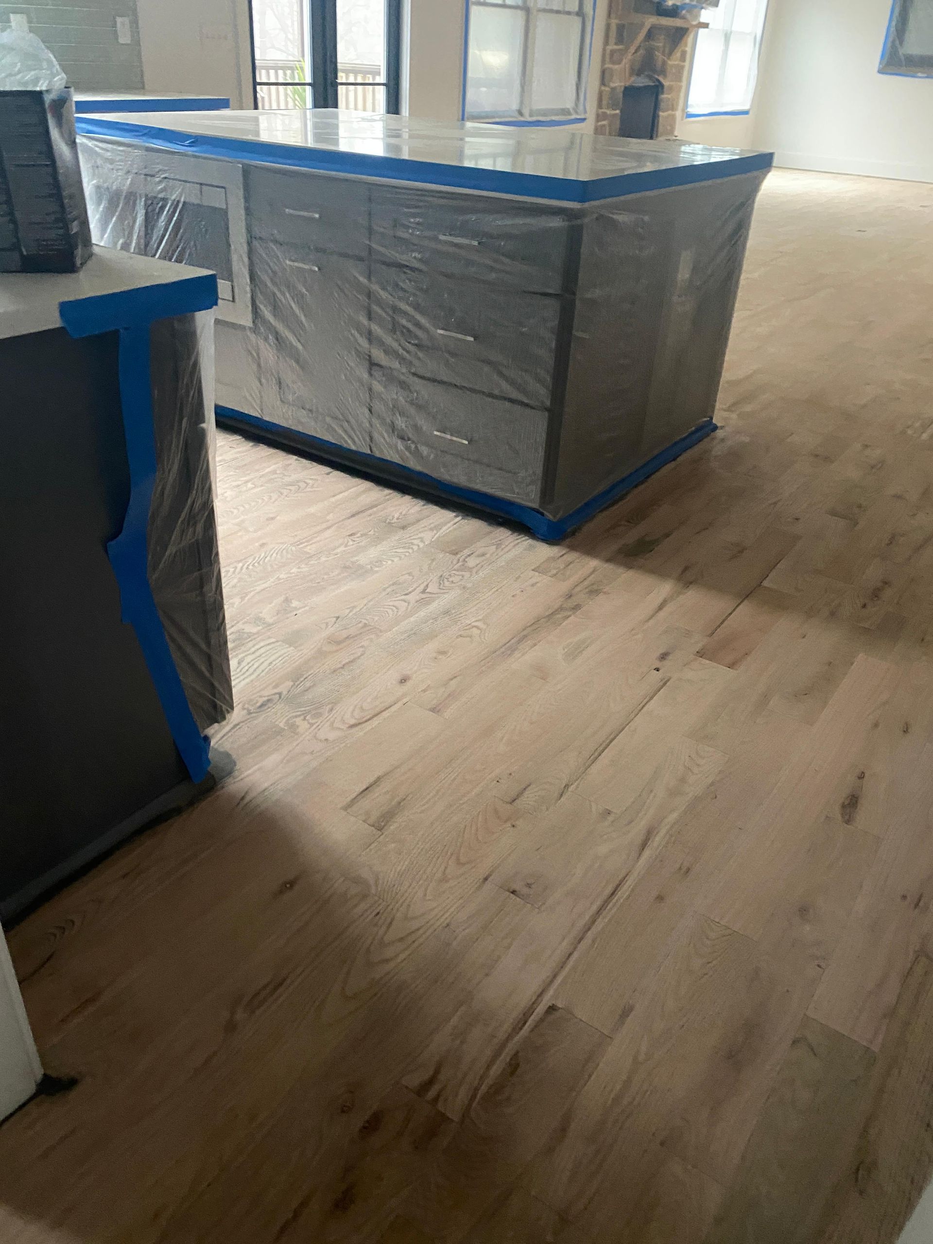 A kitchen with a large island and cabinets wrapped in plastic.