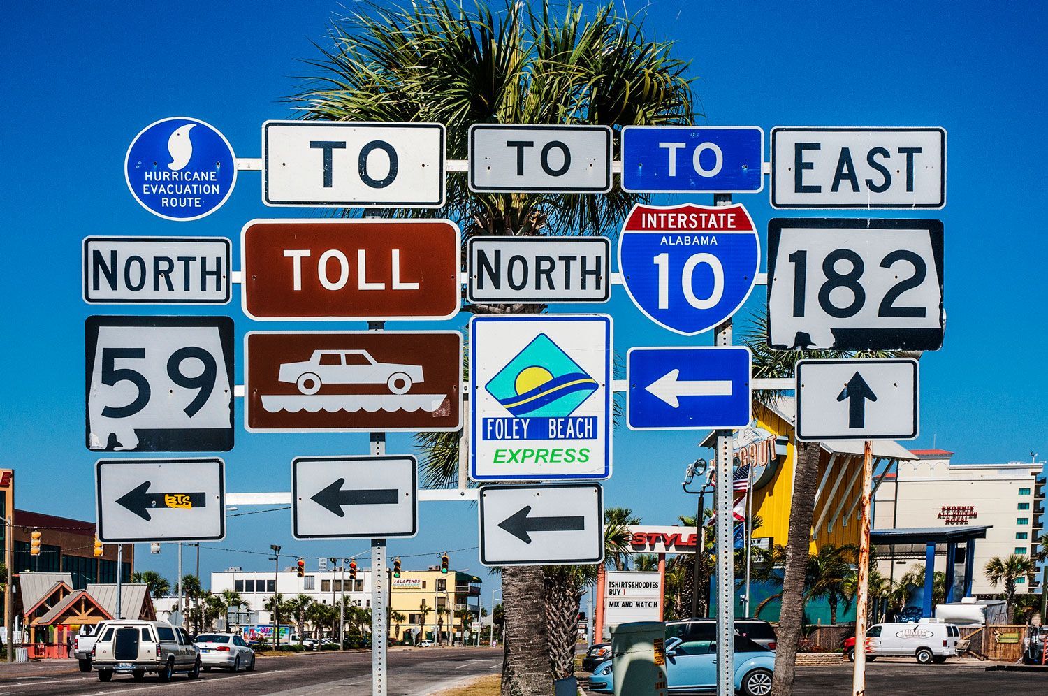 A bunch of road signs are stacked on top of each other on a street.