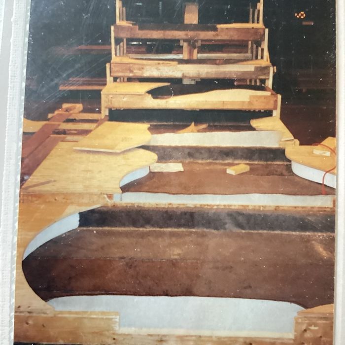 A wooden stage structure under construction, featuring multiple tiered levels with exposed framing and plywood flooring.