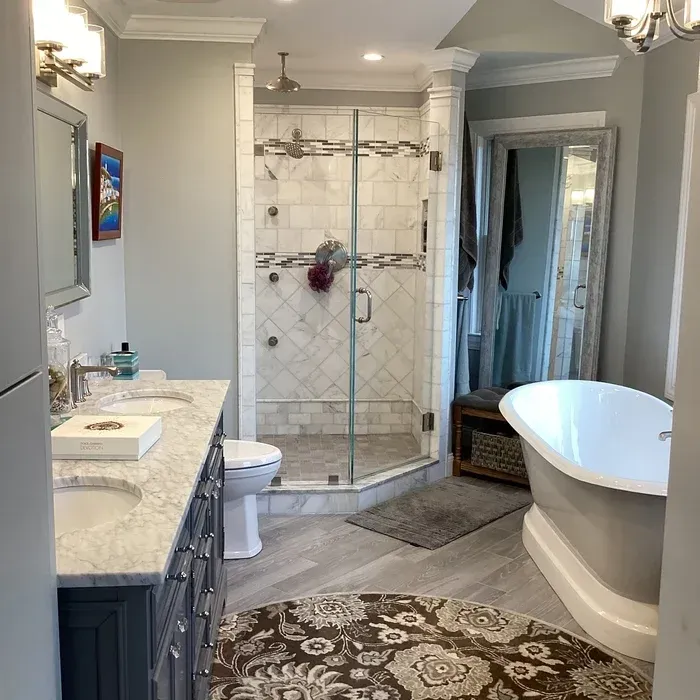 A master bathroom with a double vanity, a tiled glass shower, and a white soaking tub on a patterned area rug.