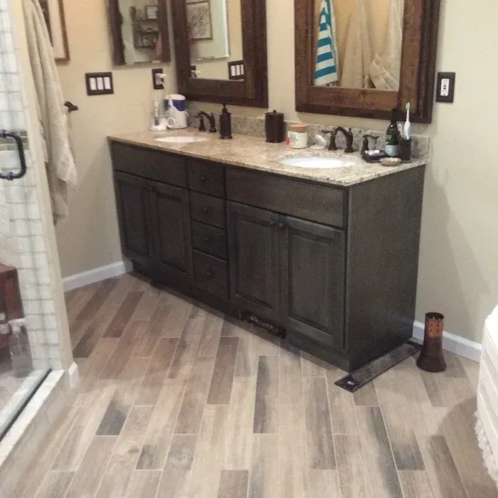 A modern bathroom featuring a dark wood double vanity with a speckled countertop, dual sinks, and wood-framed mirrors.
