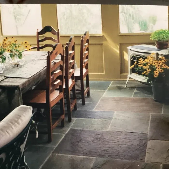 Sunroom with a wooden dining set, stone tile flooring, and a white heater with yellow flowers nearby.