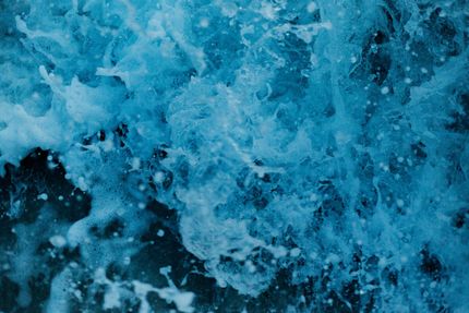 Turquoise ocean water splashing, creating white foam and bubbles ready for efoil lessons. 
