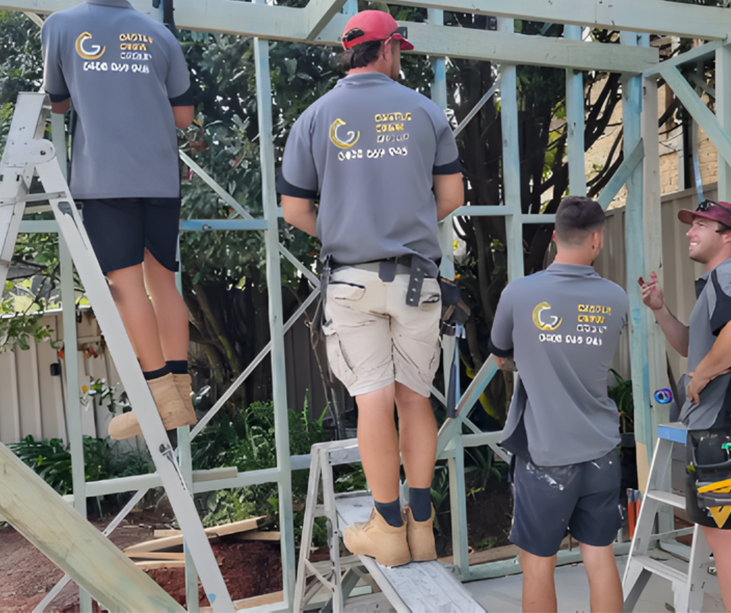Three workers in gray shirts and safety harnesses stand on scaffolding, working on a metal structure.
