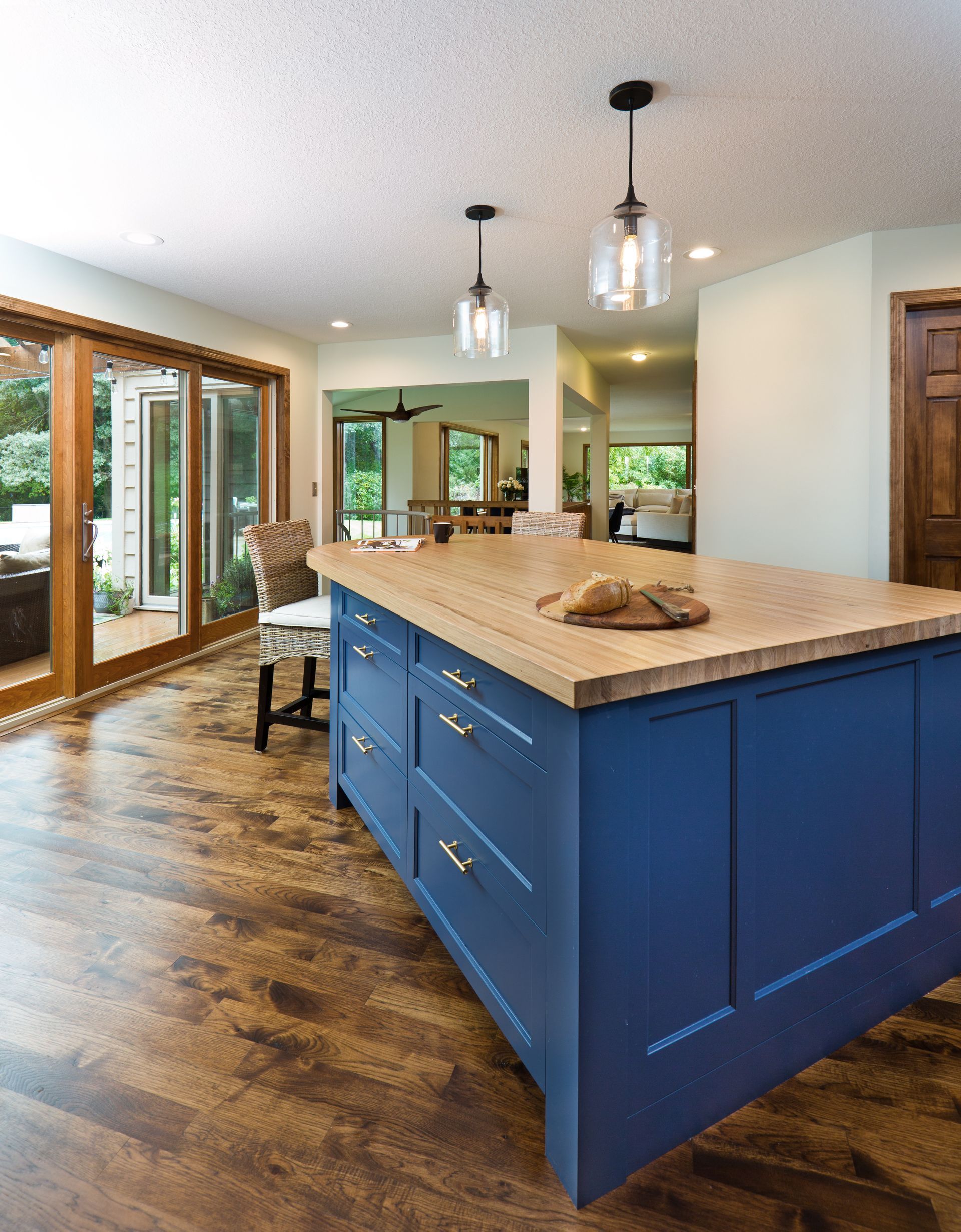 Blue kitchen island with butcher block countertop, pendant lights, and hardwood floor.