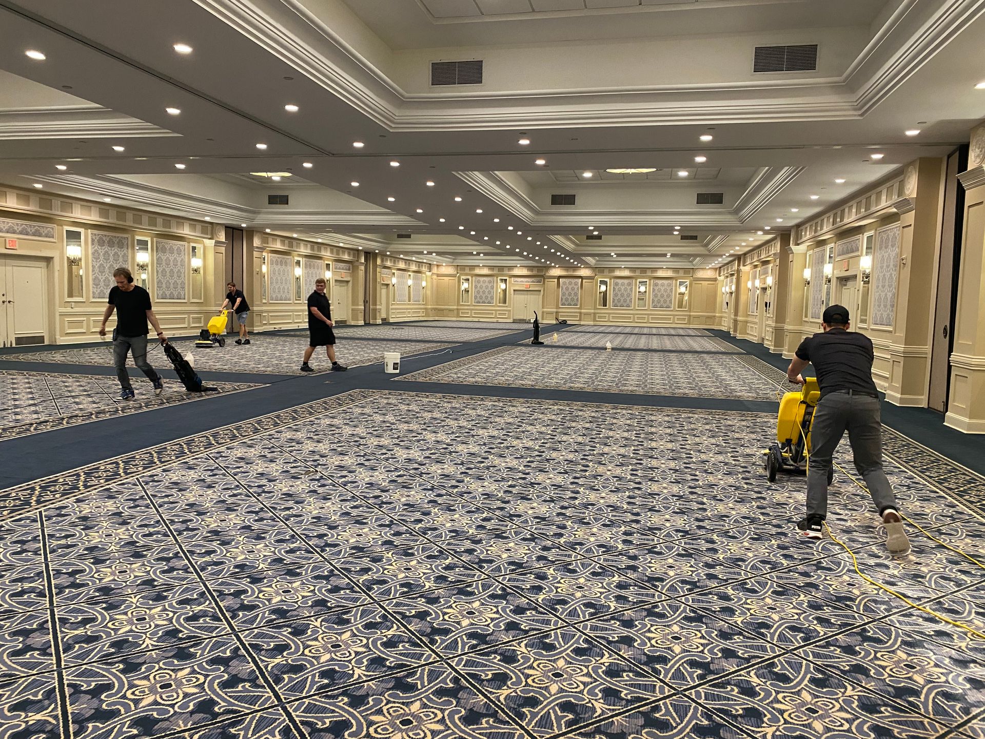 A group of people are cleaning a large room with a vacuum cleaner.