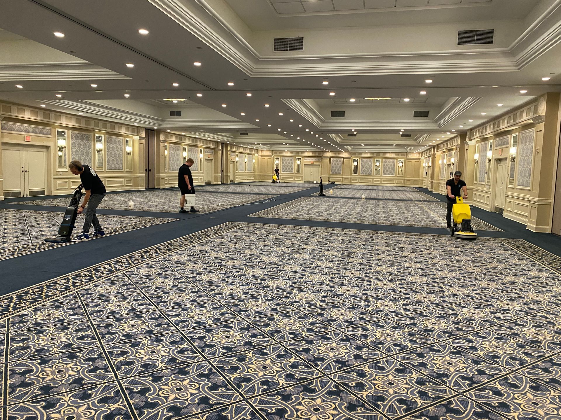 A group of people are cleaning a large room with a vacuum cleaner.