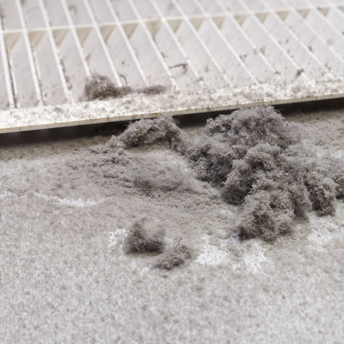Gray dust or debris piled on a carpeted floor near a white railing.