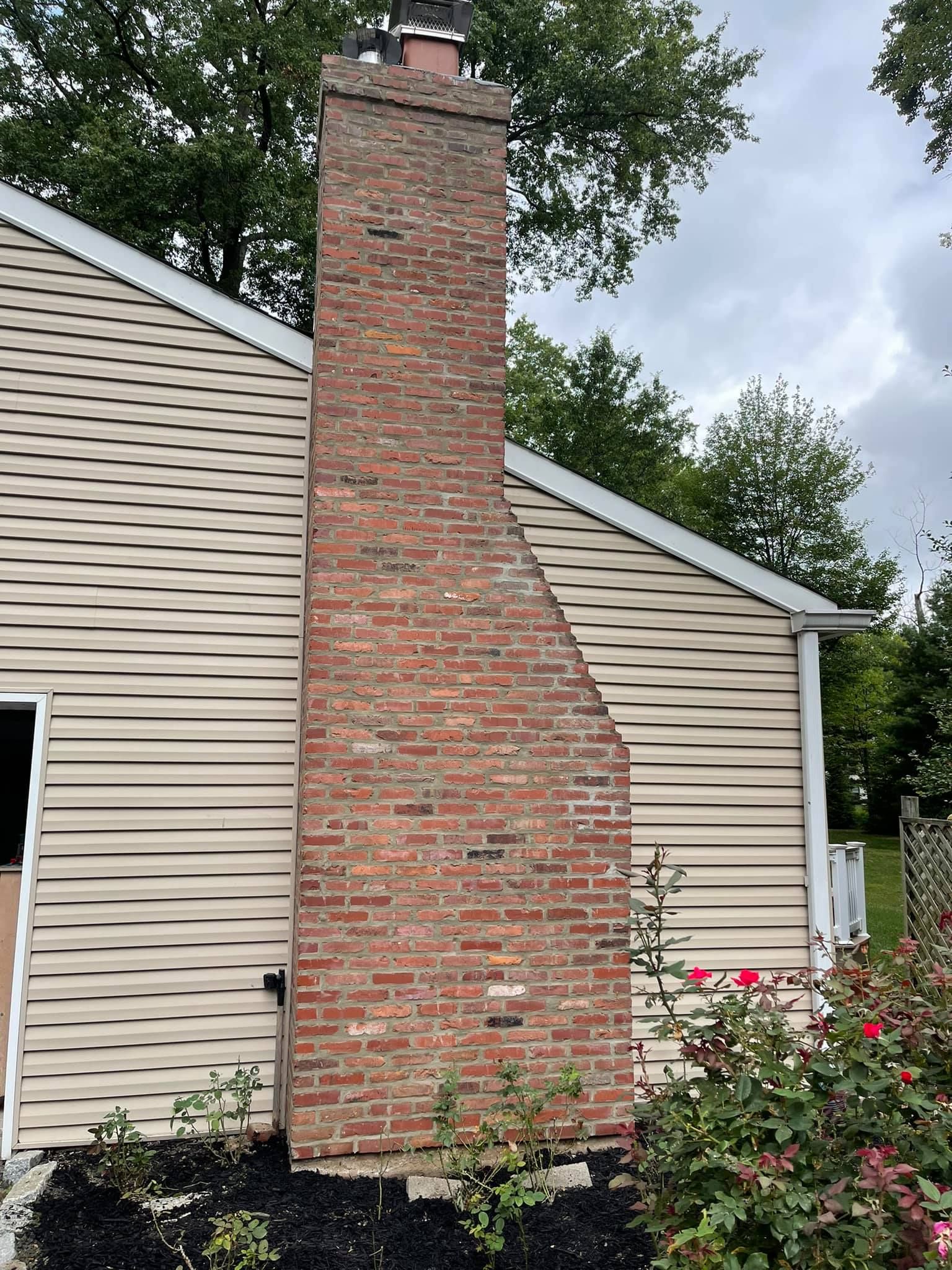 A large brick chimney is on the side of a house.