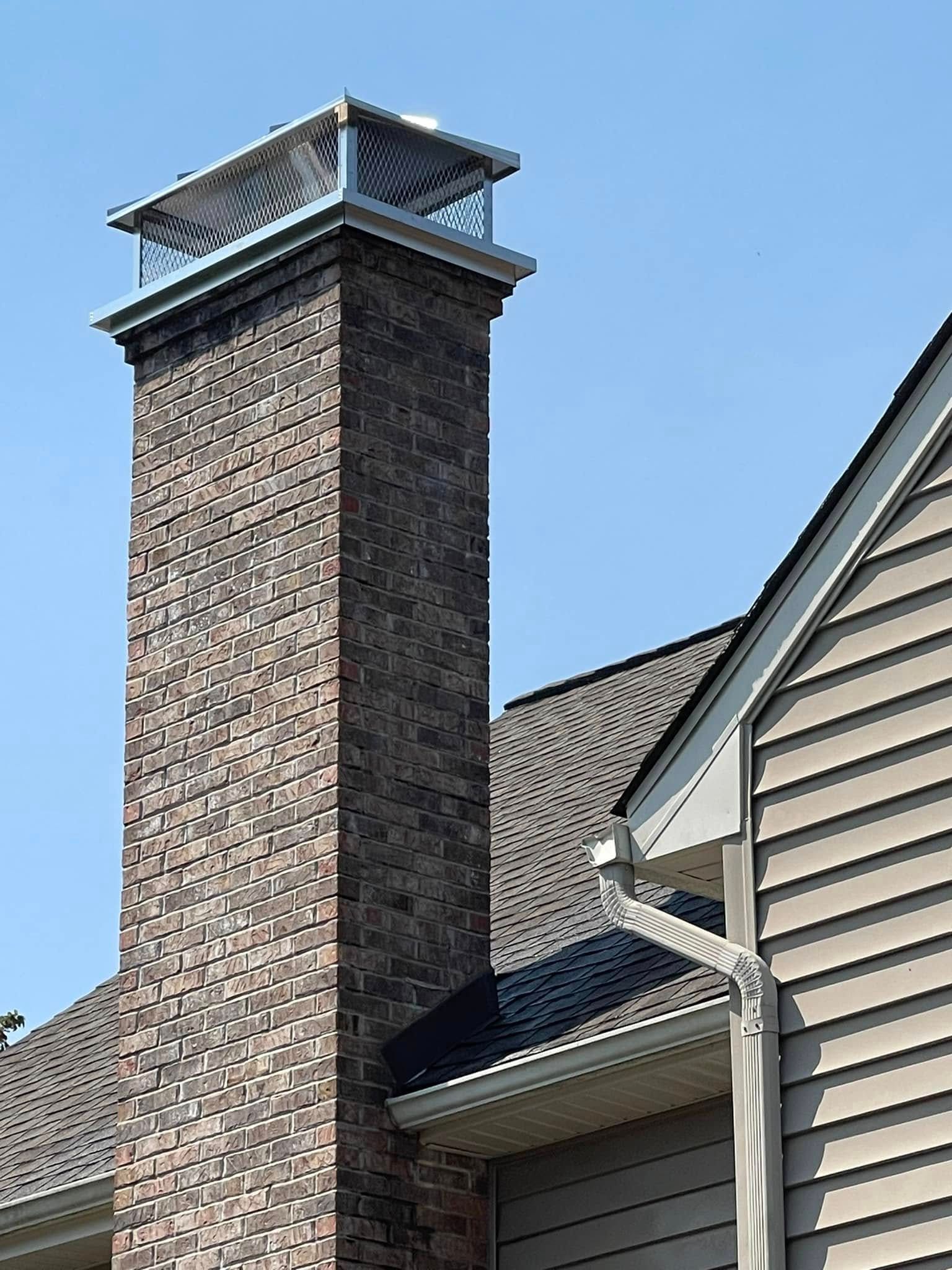 A brick chimney is on the side of a house.