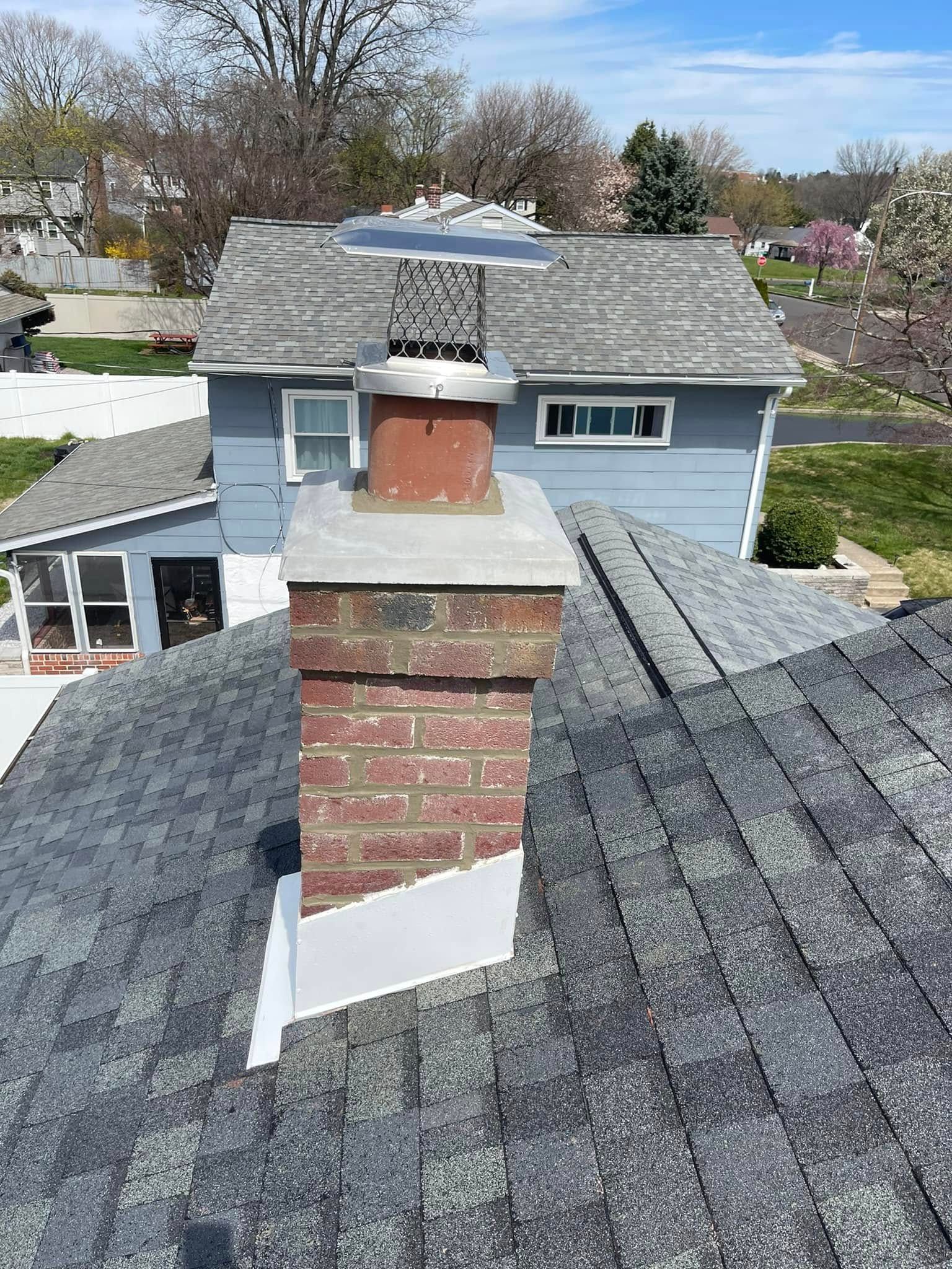A brick chimney is on the roof of a house.