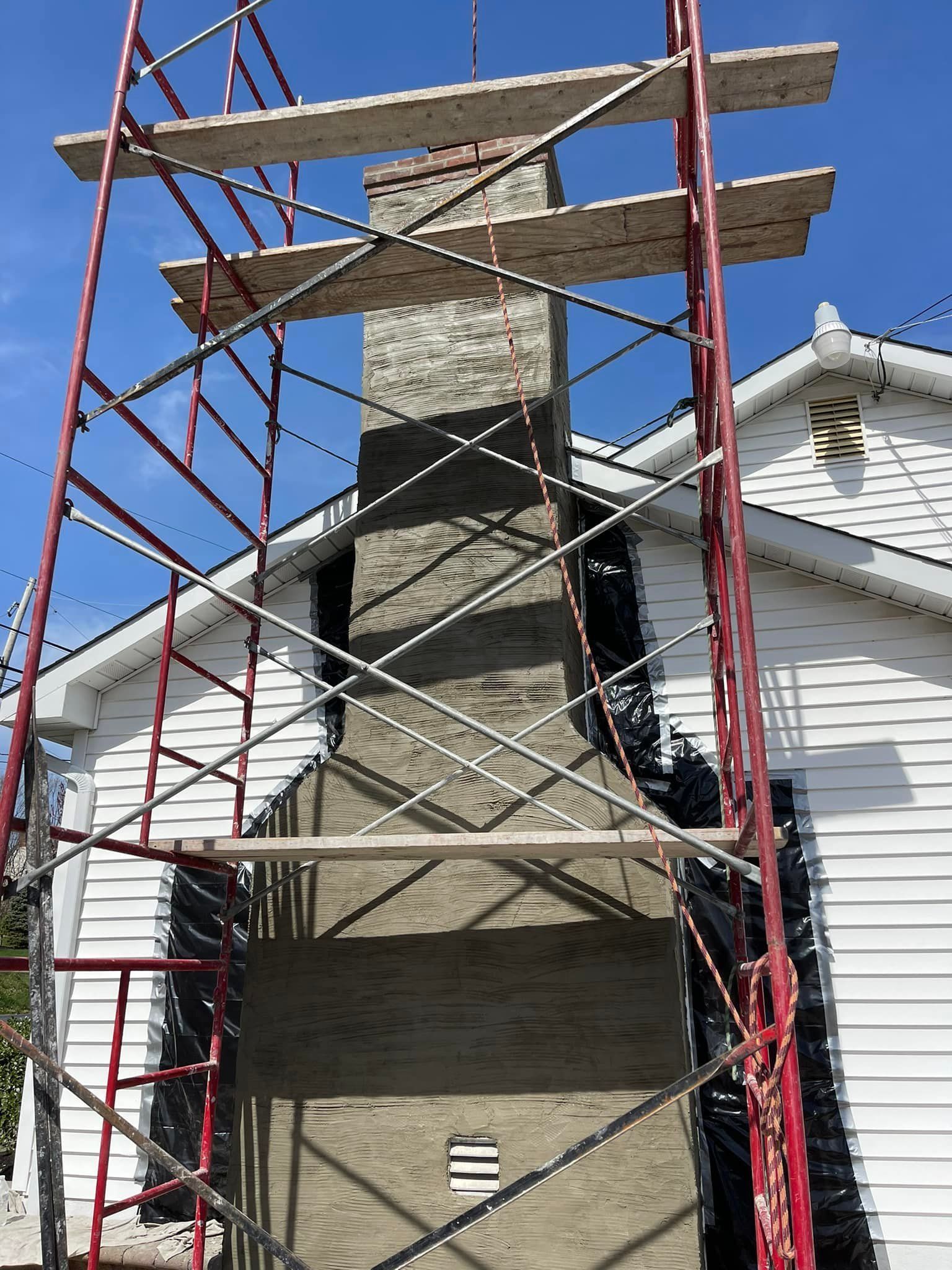 A chimney is being built in front of a white house