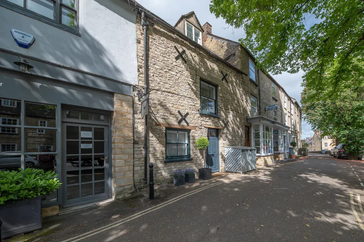 Row of stone buildings on a narrow street; sunny day.