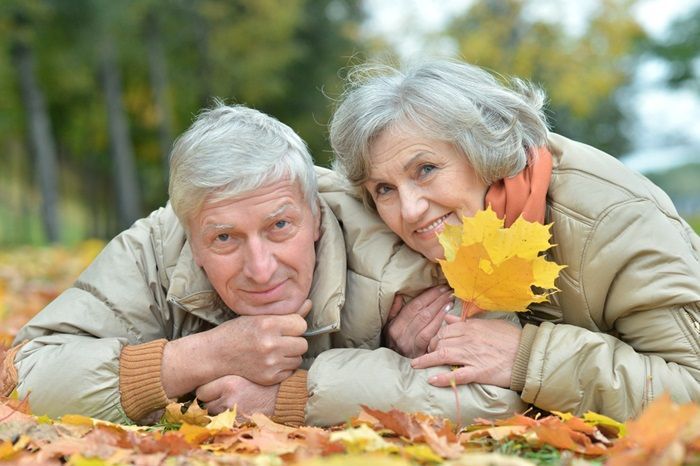 Retired couple lying on a bed of Fall leaves