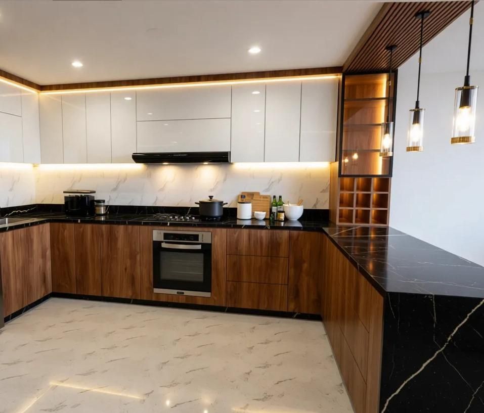 Cocina moderna con gabinetes blancos, encimeras negras, detalles en madera y pisos de mármol.