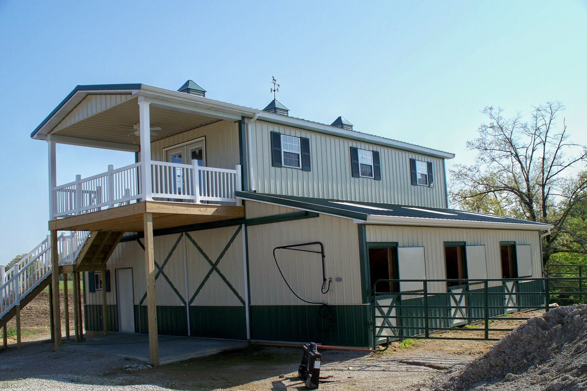 Two-story house with a wraparound porch and exterior stairs in a rural setting
