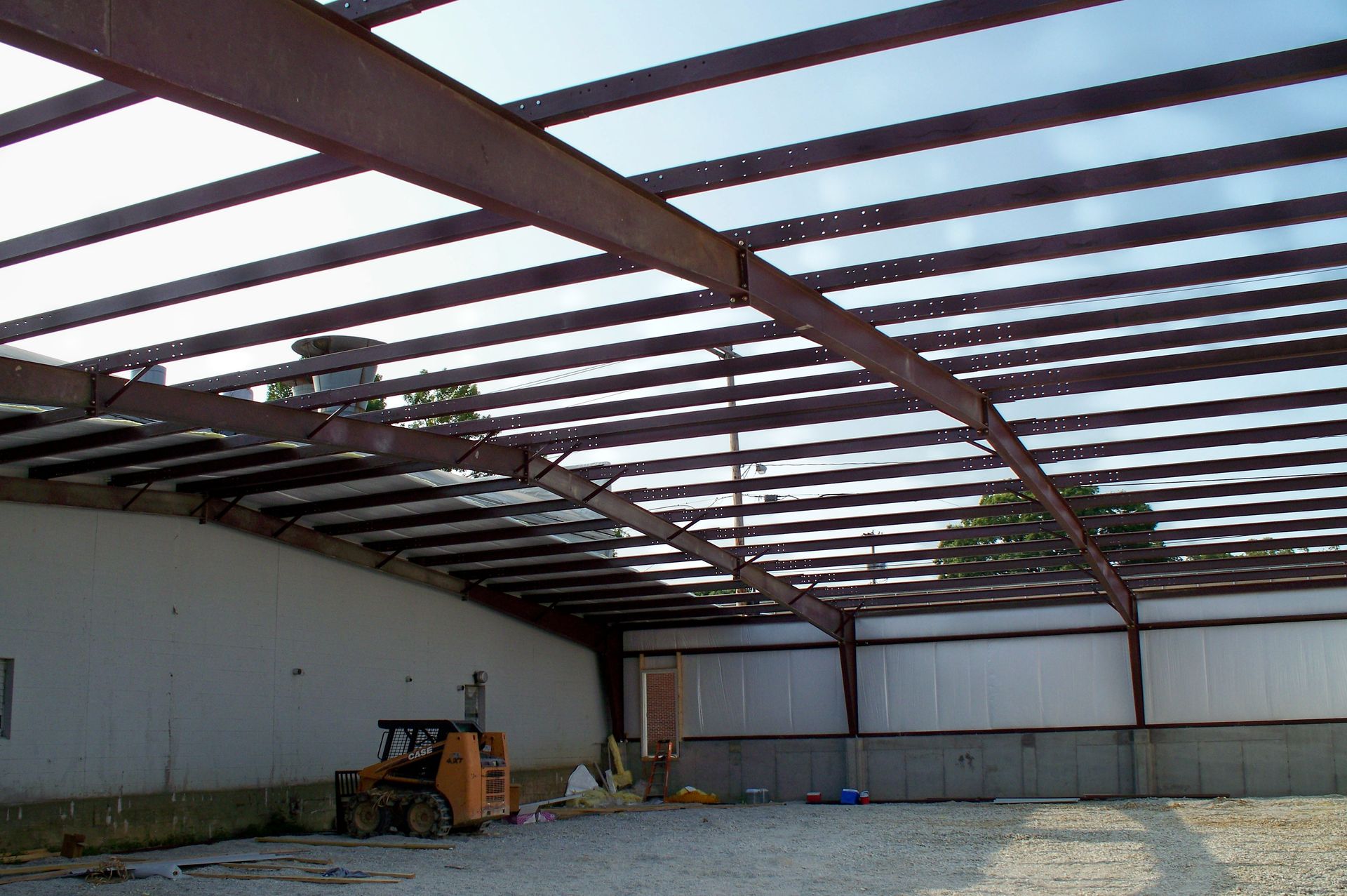 Empty warehouse with steel roof beams and a concrete floor under construction
