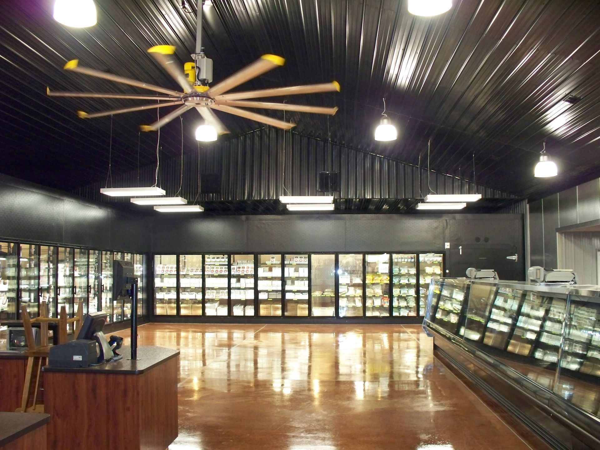Empty modern retail interior with glass display cases, polished floor, and ceiling fans in a dark showroom