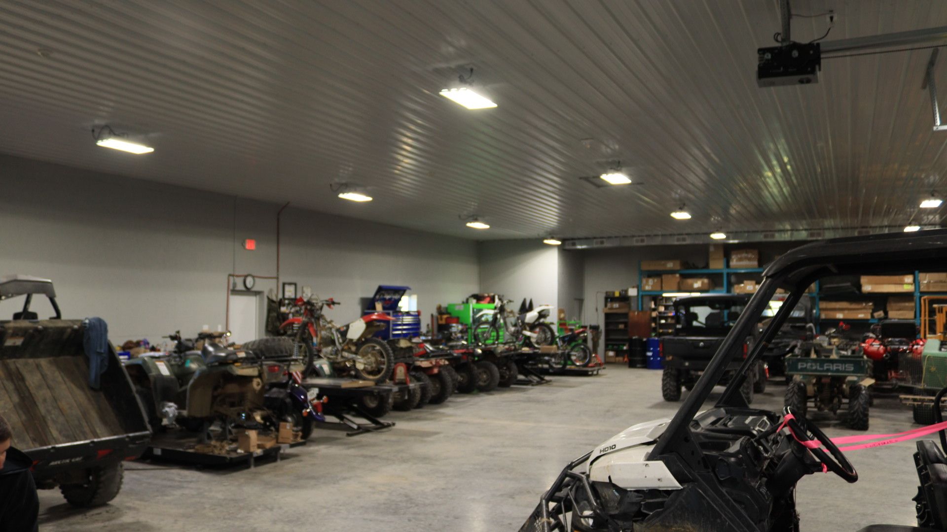 Indoor garage packed with off-road vehicles and ATVs under bright ceiling lights