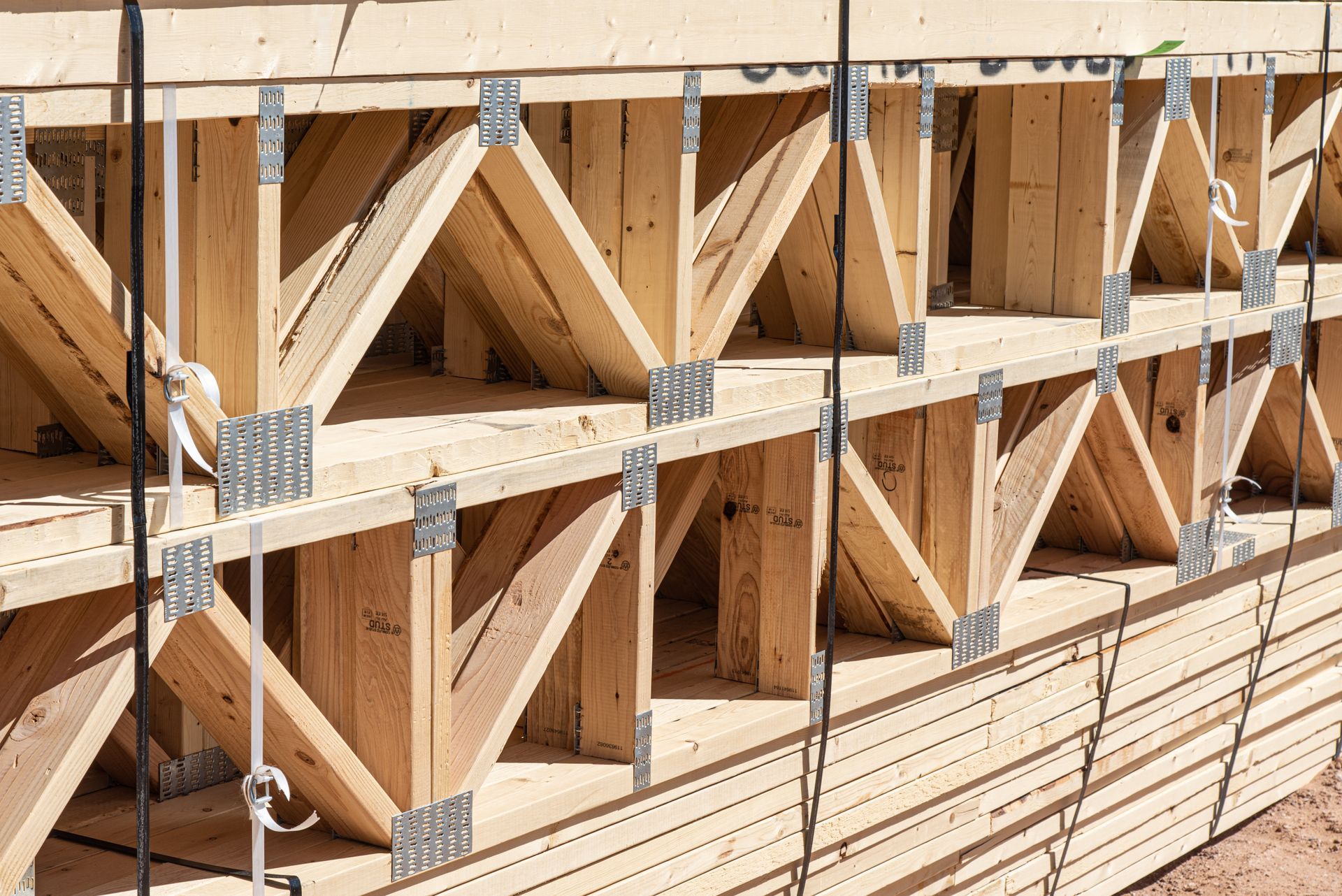 Stacked wooden floor trusses secured with metal plates at a construction site. Stacked wooden floor trusses secured with metal plates at a construction site.