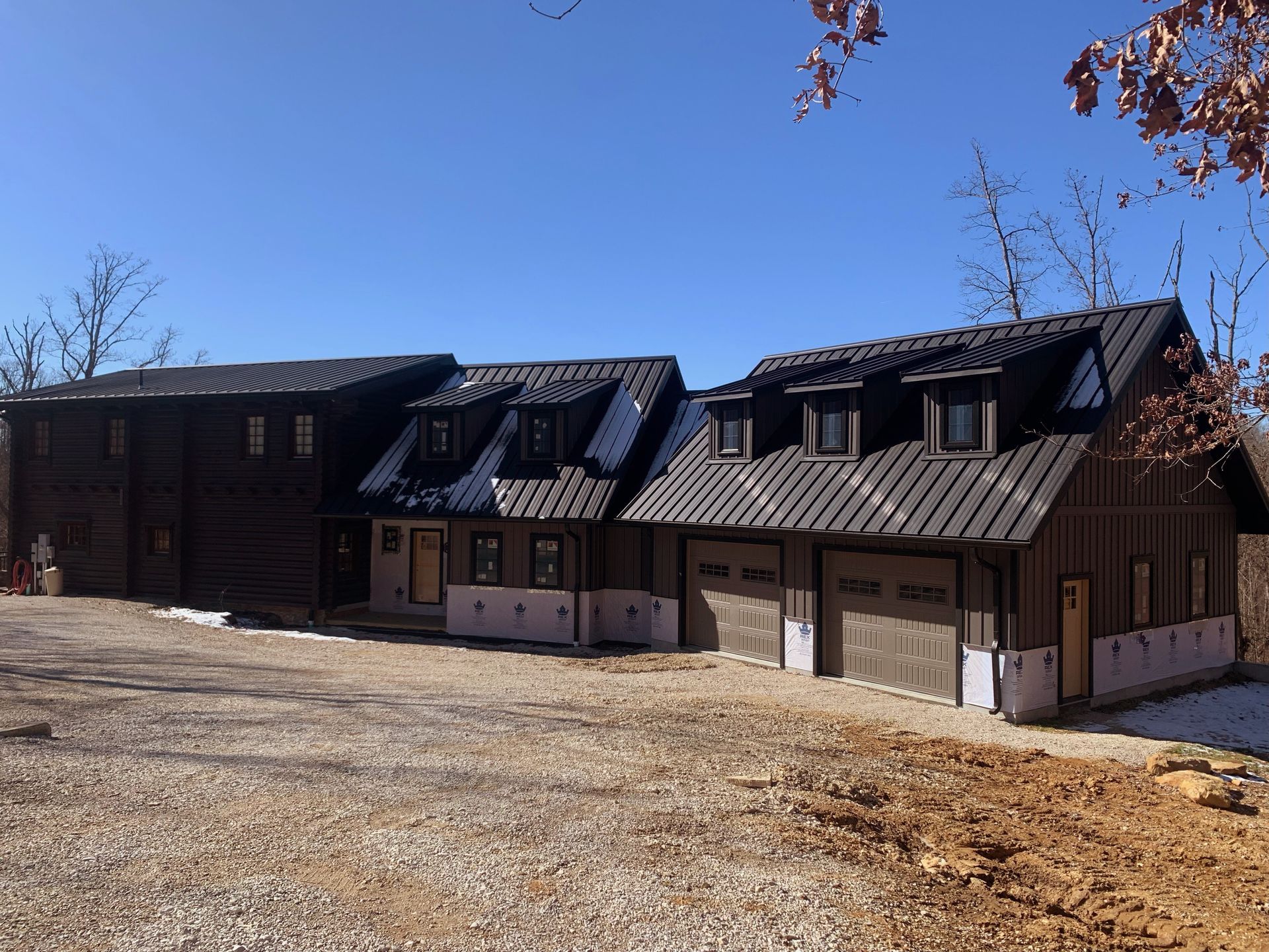 Row of dark wooden ski chalets with snow-covered roofs under a clear blue sky