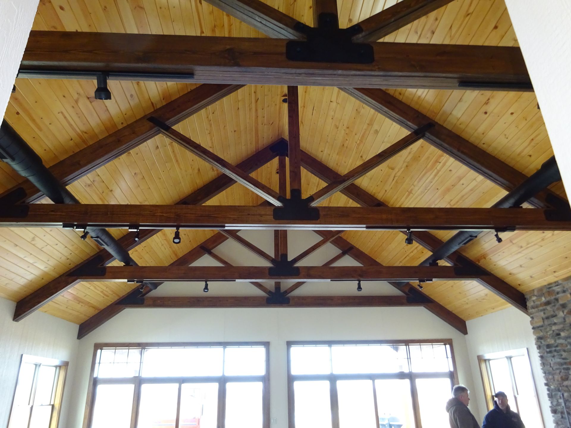 Wooden vaulted ceiling with exposed dark beams over a bright room with large windows