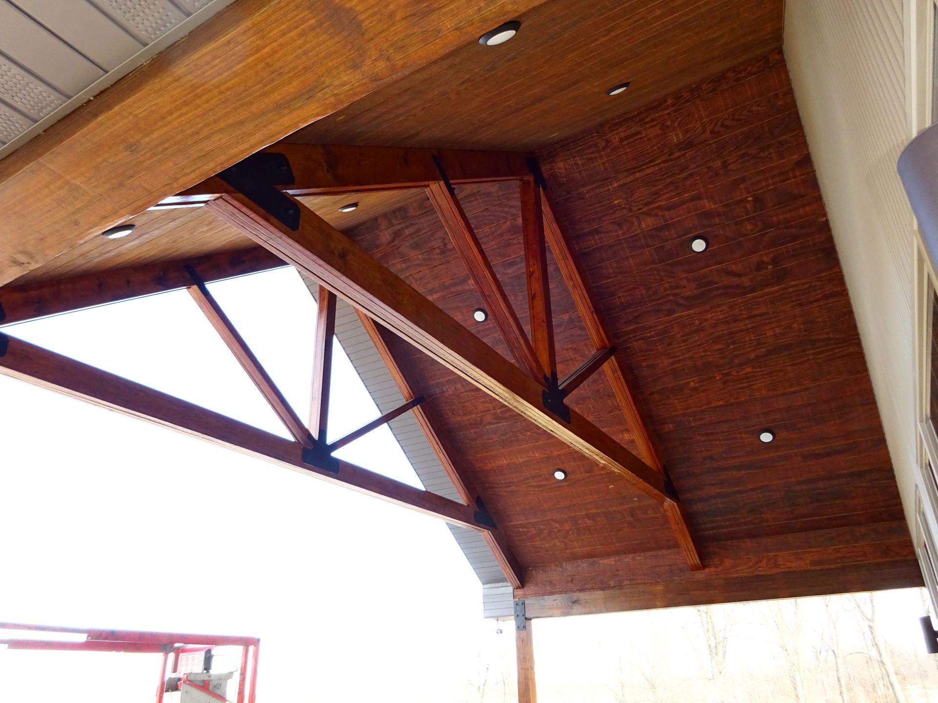 Wooden ceiling beams and trusses supporting a slanted roof, viewed from below