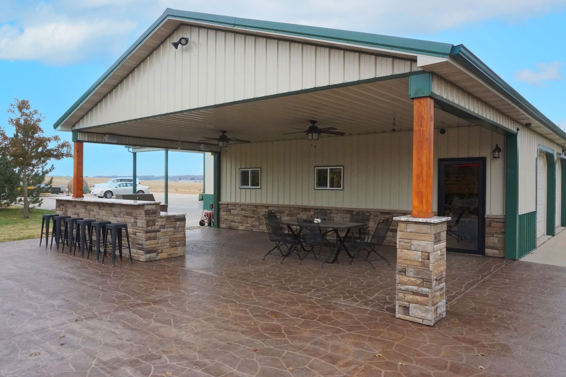 Covered patio with stone columns, bar stools, and tables on a tiled terrace overlooking the water