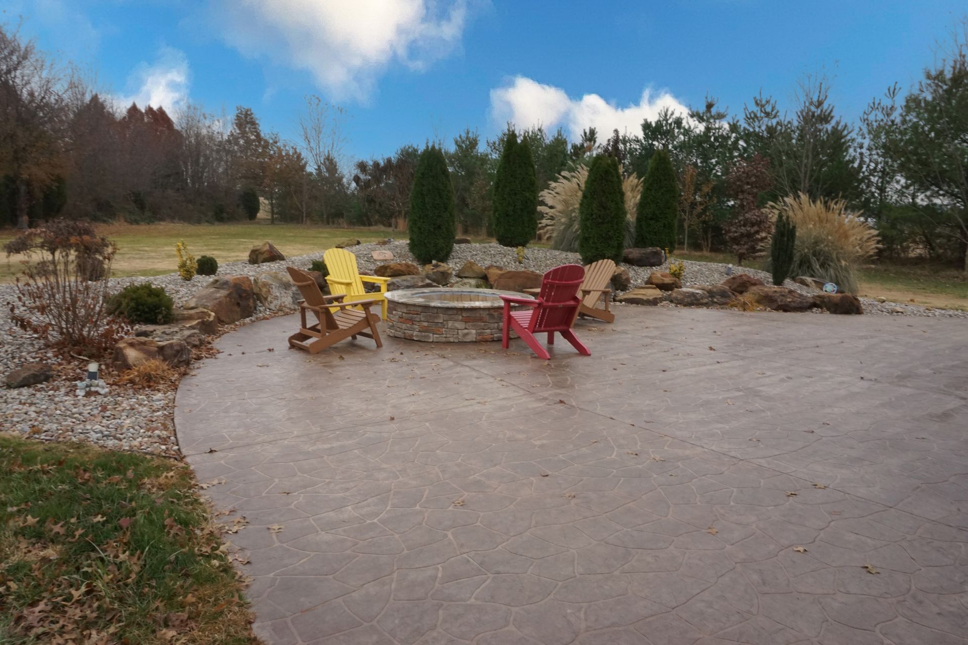 Patio with yellow and red chairs around a table in a landscaped garden under a blue sky