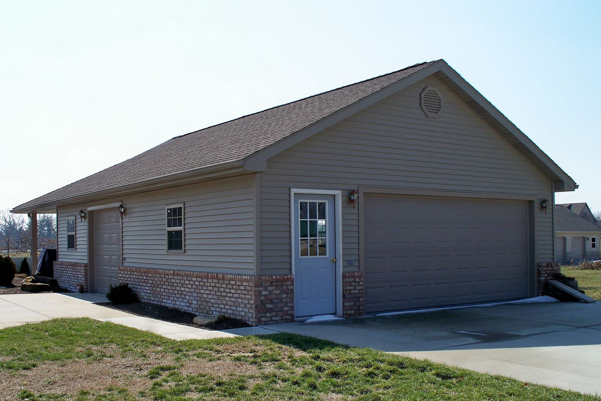 Suburban single-story house with beige siding, stone trim, and an attached two-car garage