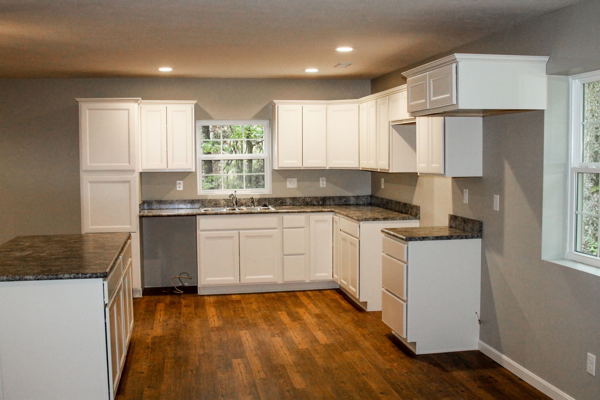 Bright kitchen with white cabinets, granite countertops, stainless appliances, and hardwood floors