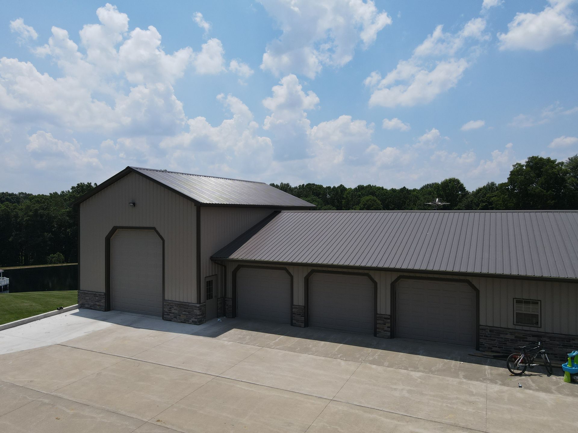 Large metal storage building with a tall garage door and covered side bays under a cloudy blue sky