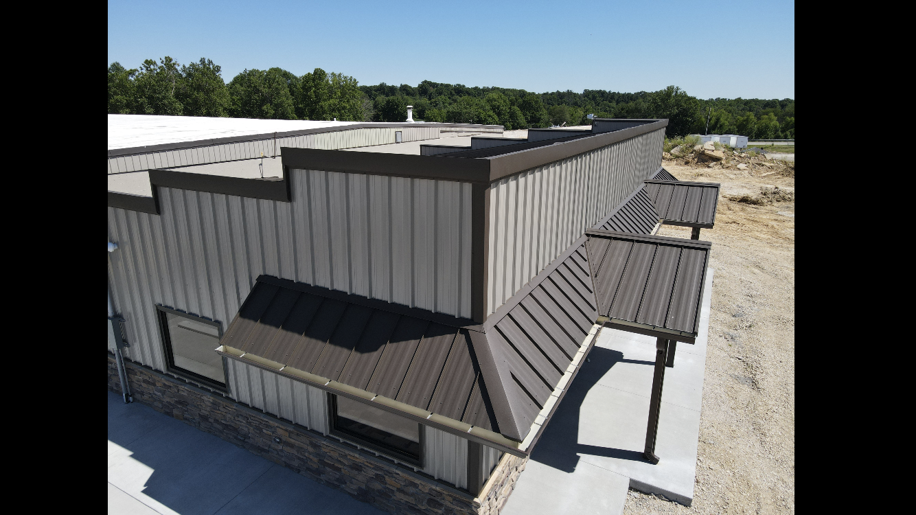 Aerial view of a gray metal-roofed industrial building with multiple roof sections and skylights.