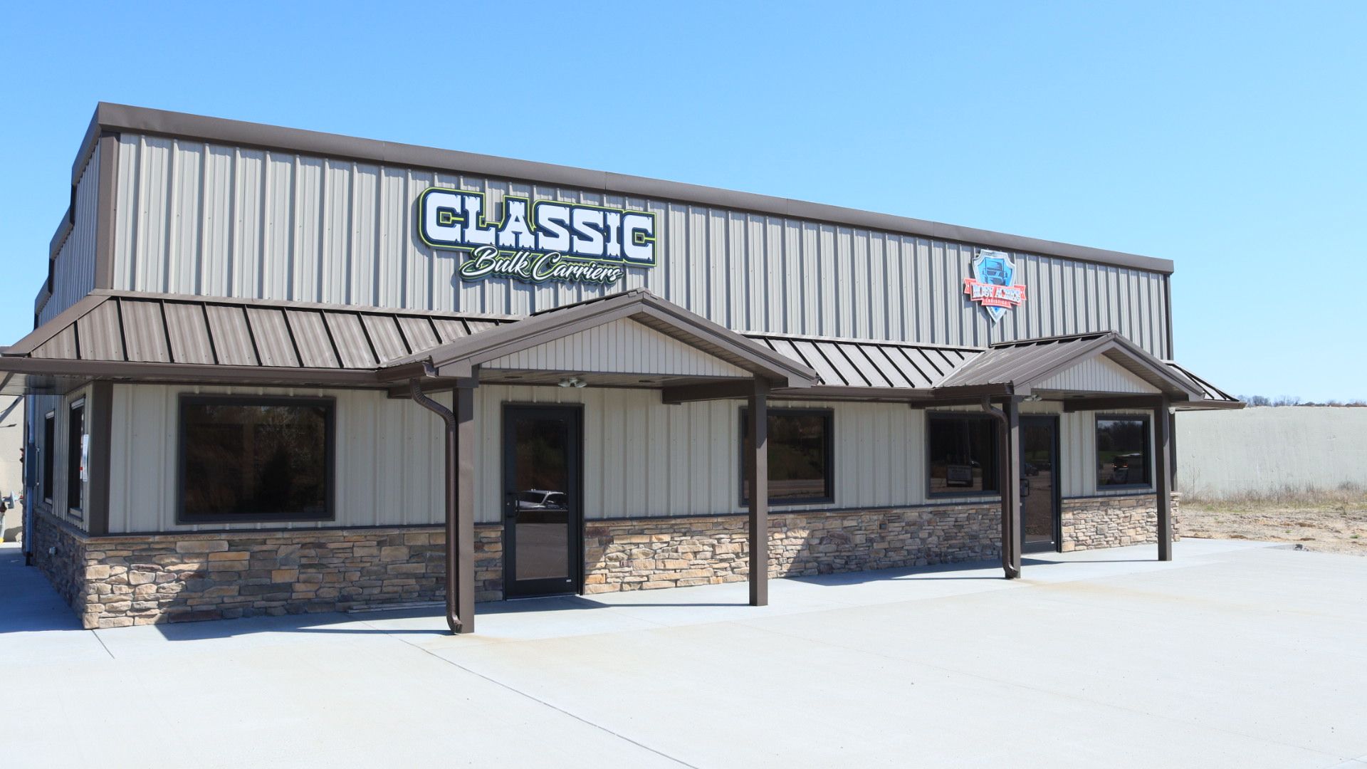 Snow-covered storefront with a “Classic” sign and striped awning under a clear blue sky