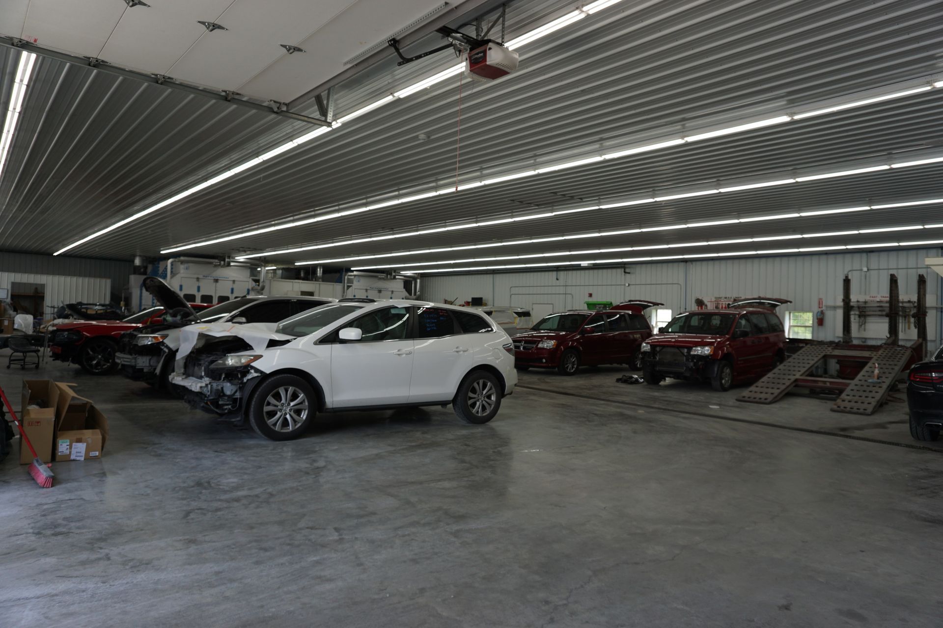Car lot showroom with white SUV in front and rows of parked cars under bright ceiling lights