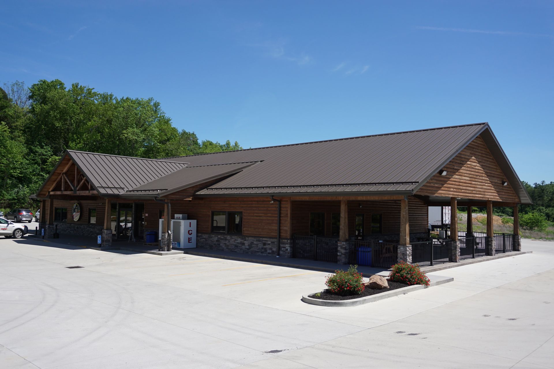 Rustic brick building with a dark roof and covered porch on a sunny day