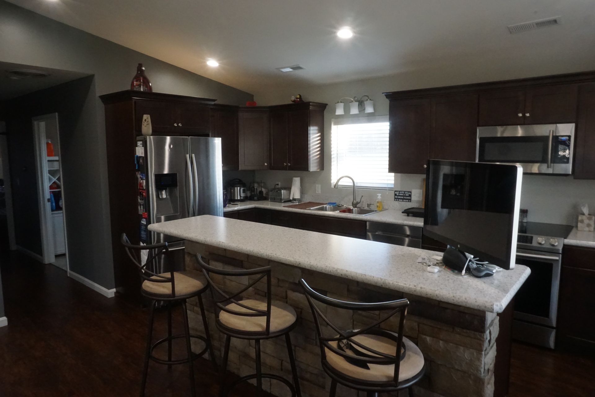 Modern kitchen with dark cabinets, stainless appliances, and a granite island with bar stools