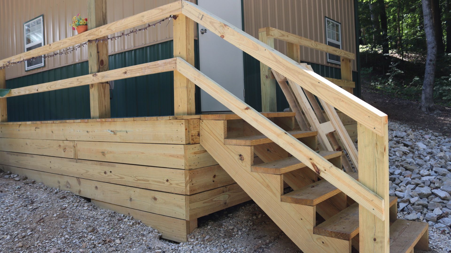 Wooden wheelchair-accessible ramp and stairs leading to a cabin porch in a wooded area