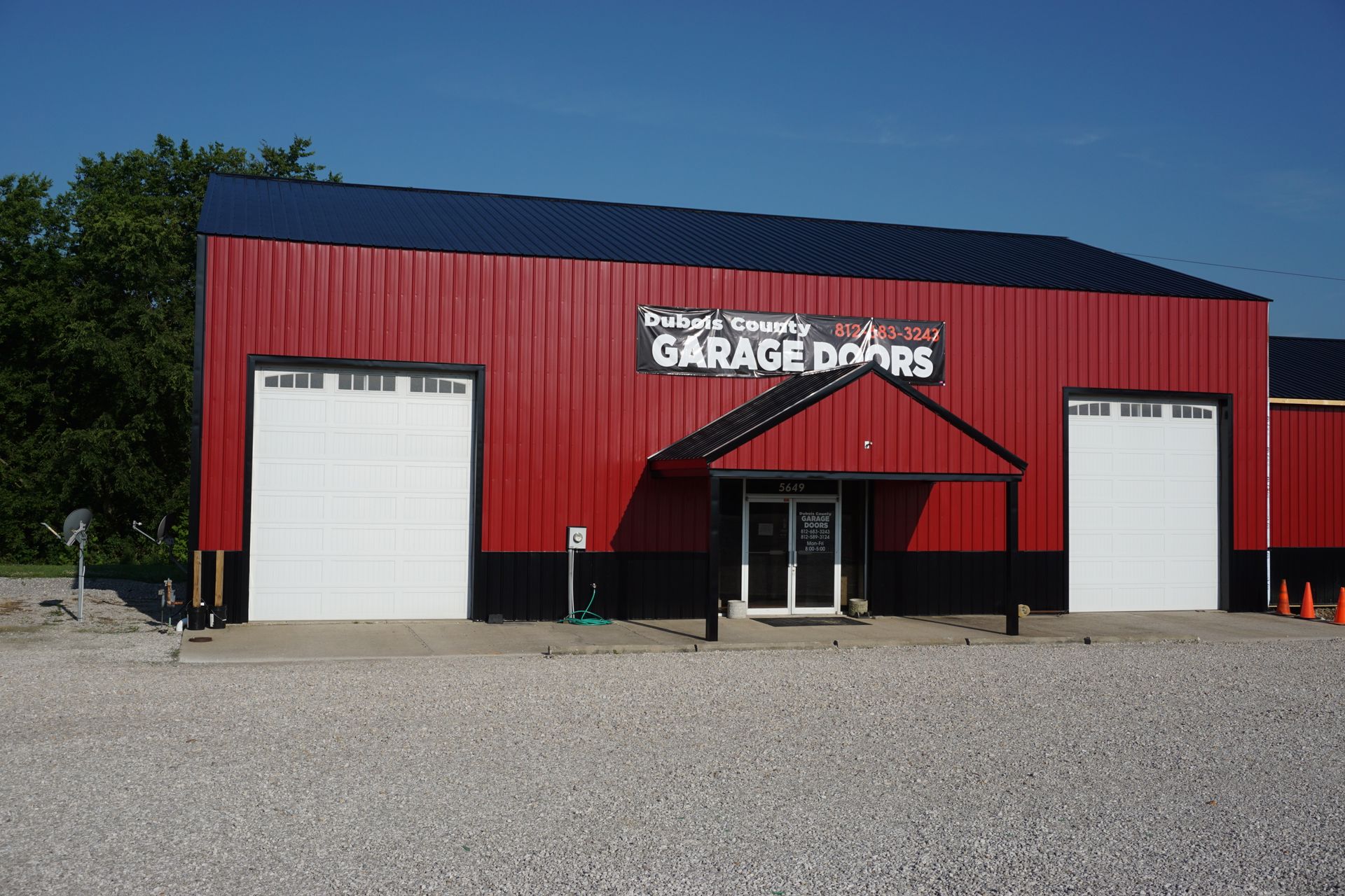 Red garage building with a central entrance and white garage doors under a blue sky