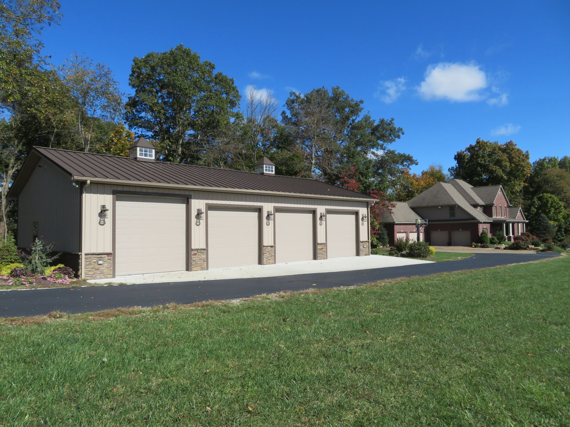 Single-story beige garages beside a house, with a green lawn and blue sky on a sunny day