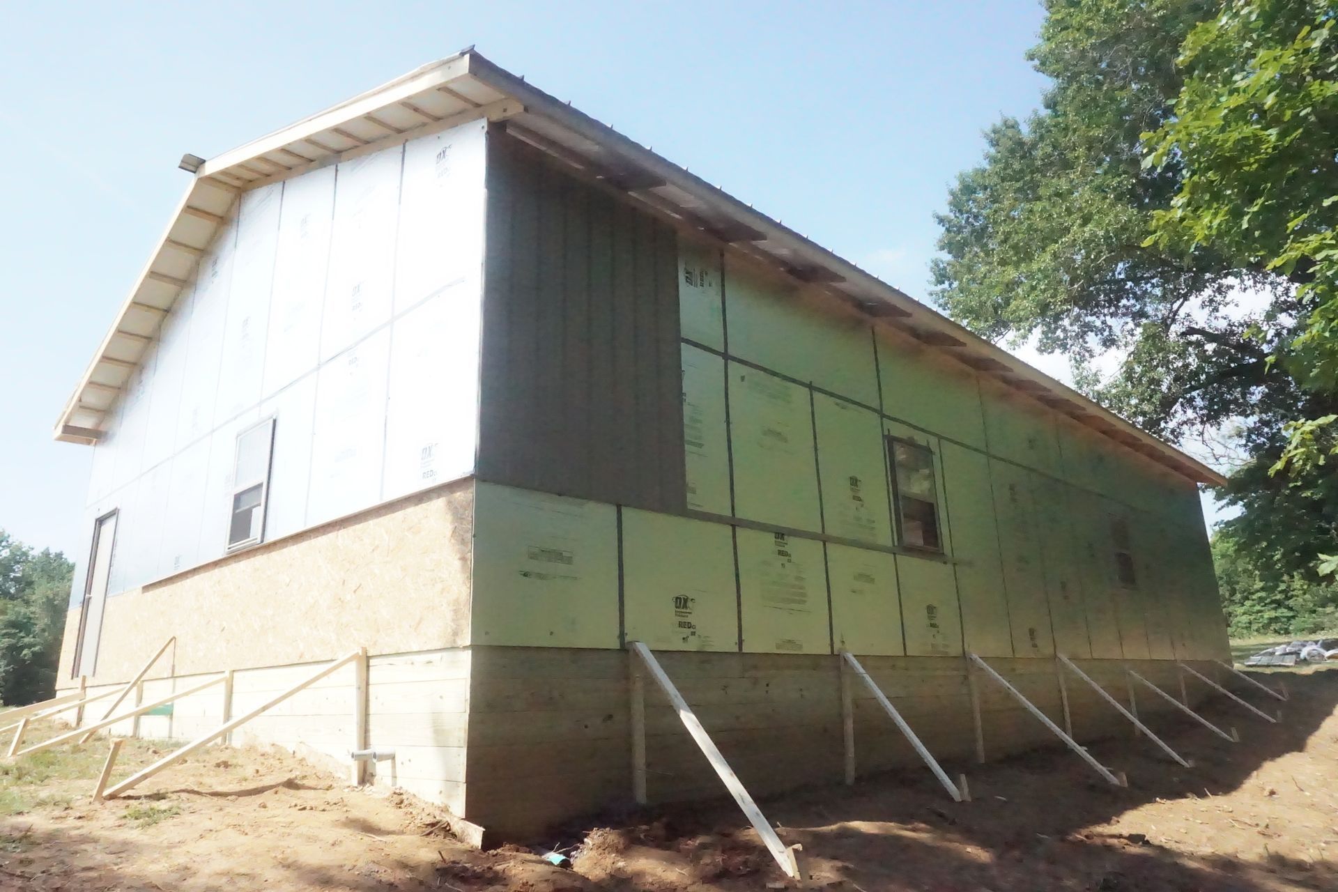 White and green barn-like building on a dirt slope under a clear sky