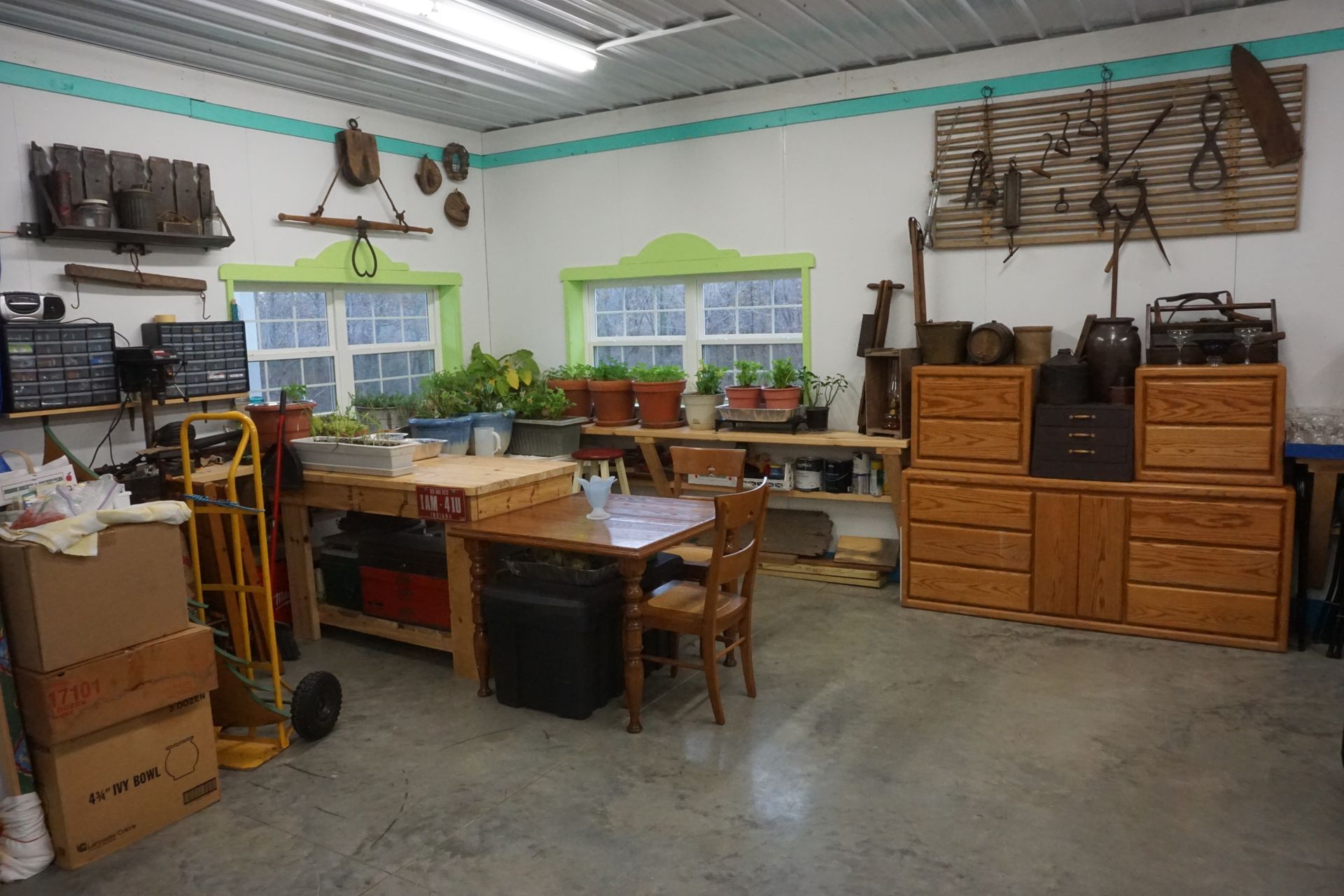 Garage workshop with wooden cabinets, workbenches, tools, and windows along the back wall.