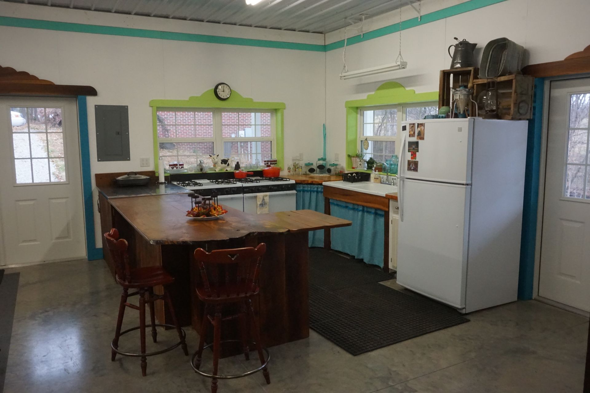 Bright kitchen with wooden island, white fridge, blue trim, and large window over the sink.