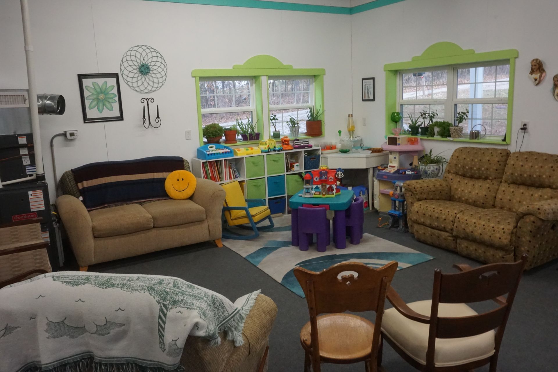 Bright playroom with toys, colorful chairs, couches, and large windows.