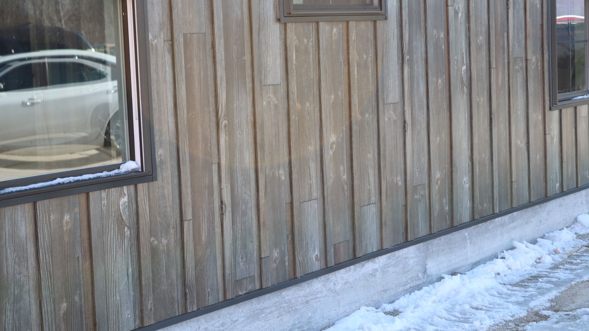 Wooden building exterior with a window and snow along the baseboard