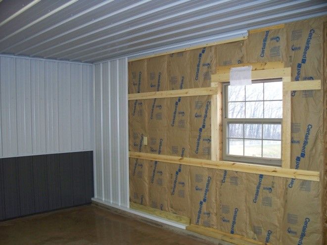 Interior wall under construction with exposed insulation and a window opening in a small room