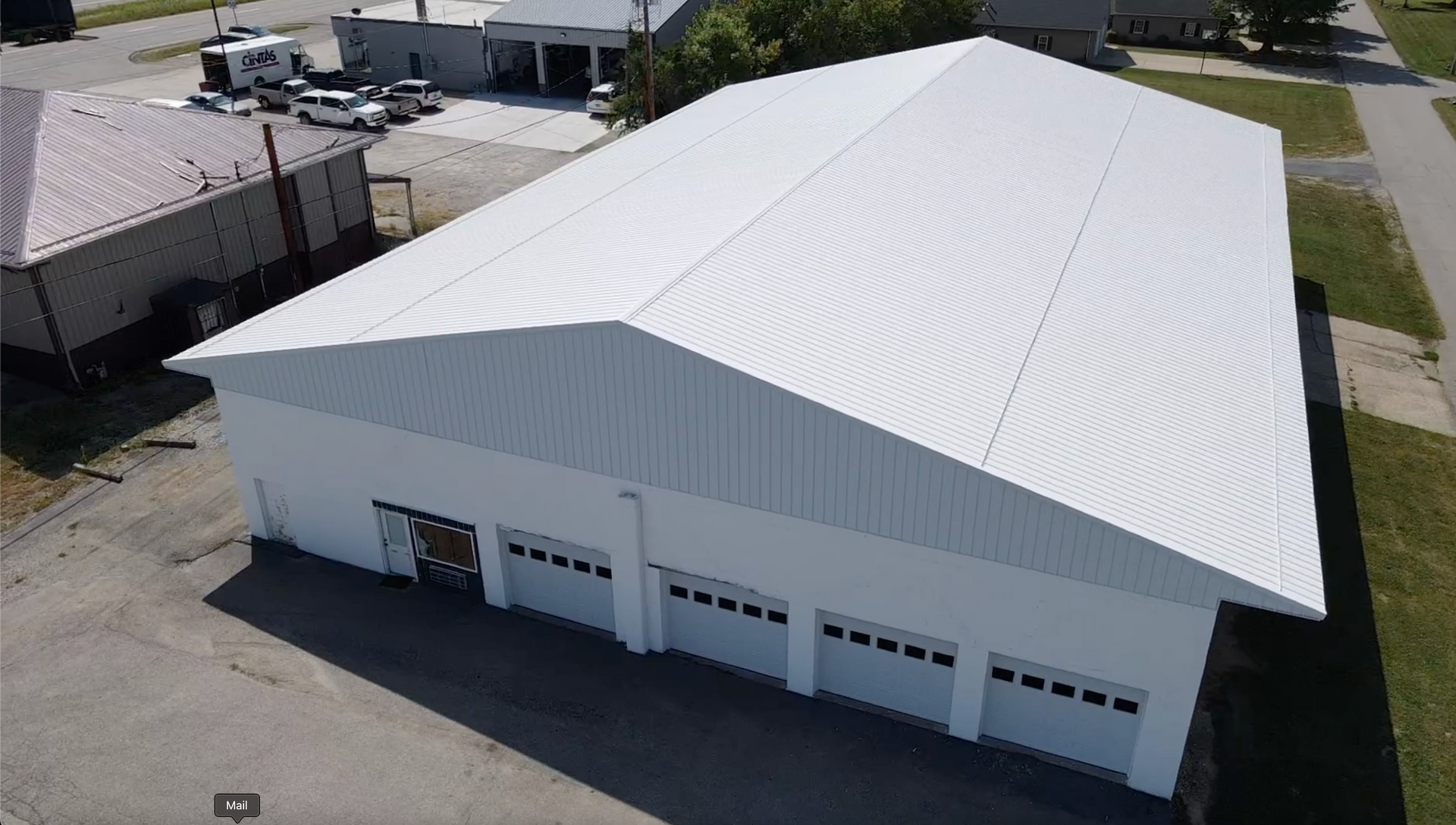 Aerial view of a large white industrial warehouse with a curved roof and multiple garage doors.