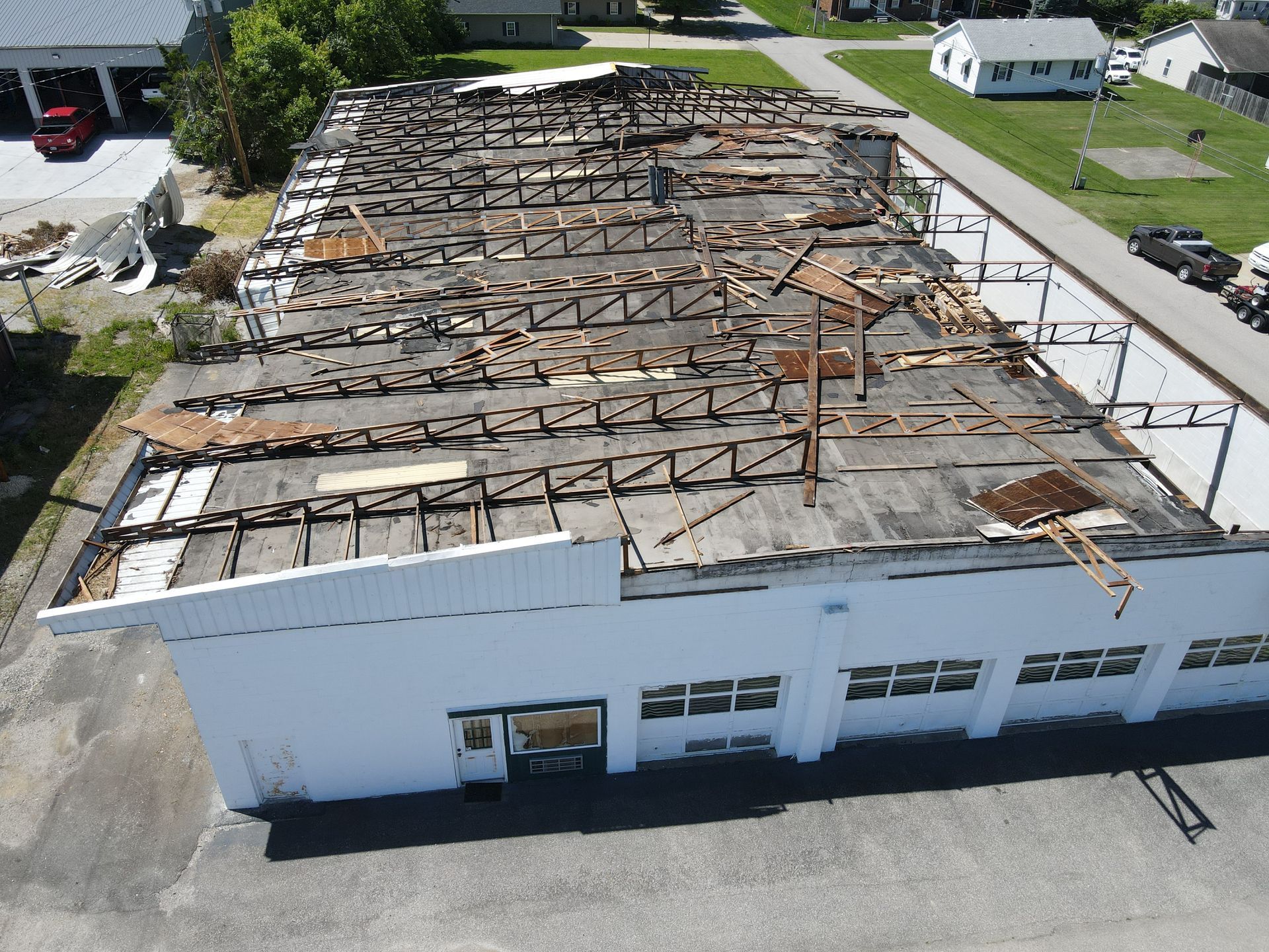 Aerial view of a damaged white building with a collapsed roof and exposed trusses.