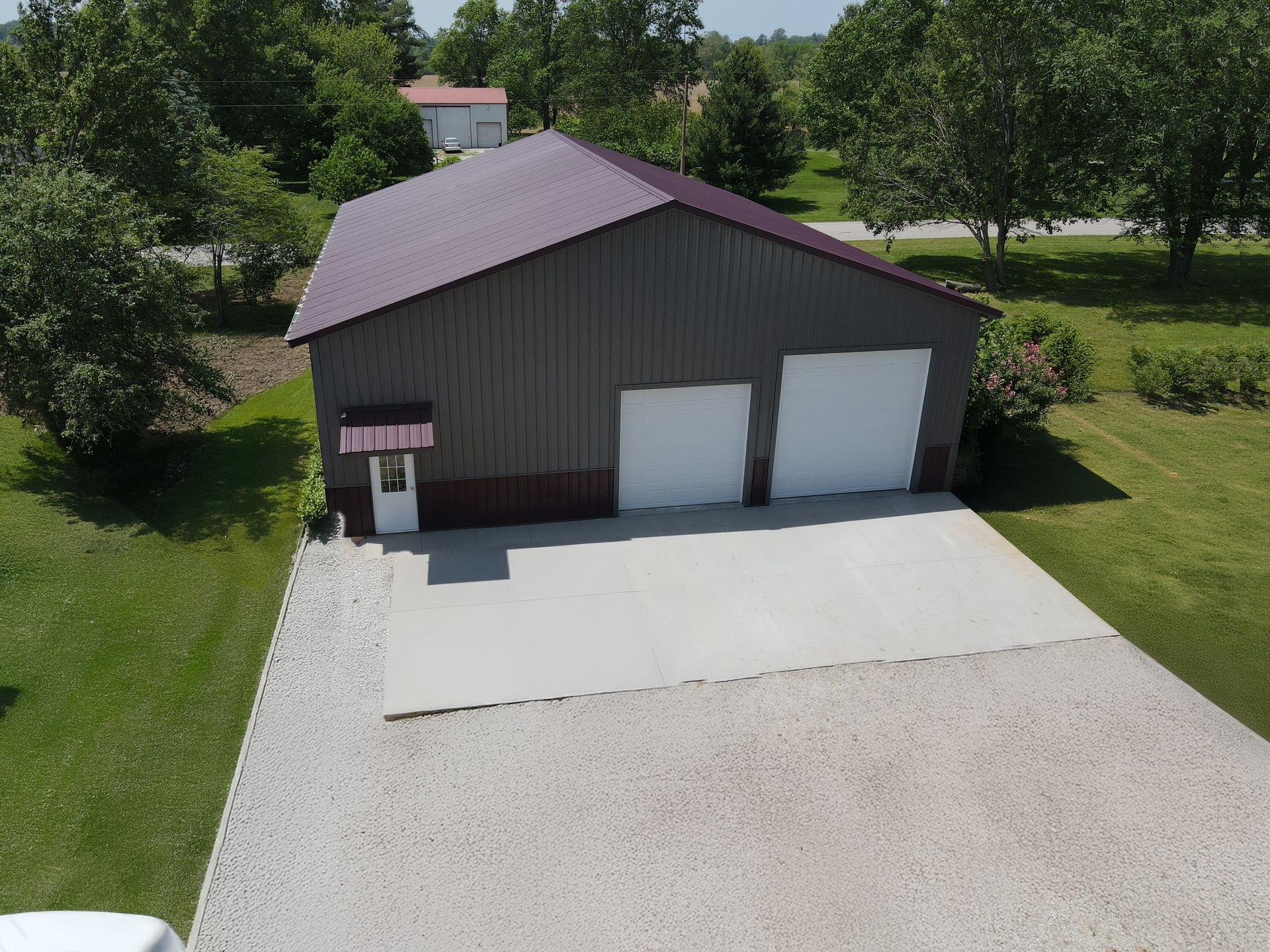 Aerial view of a brown metal garage with two white doors and a large gravel driveway.